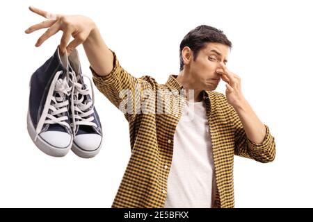 Ragazzo che tiene un paio di formatori puzzolenti isolato su bianco sfondo Foto Stock