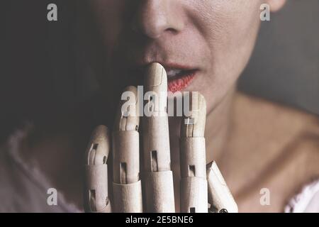 momento surreale di una mano di legno che tocca la bocca di una donna Foto Stock