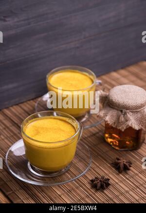 Due tazze di vetro con una bevanda disintossicante asiatica alla moda a base di latte di mandorle con spezie curcuma. Latte dorato. Foto Stock