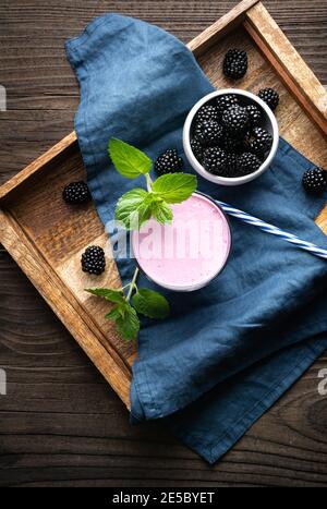 Dolce bevanda casearia, frullato di mora in un bicchiere su sfondo di legno Foto Stock