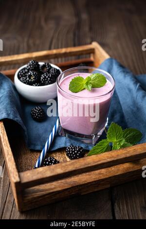 Dolce bevanda casearia, frullato di mora in un bicchiere su sfondo di legno Foto Stock