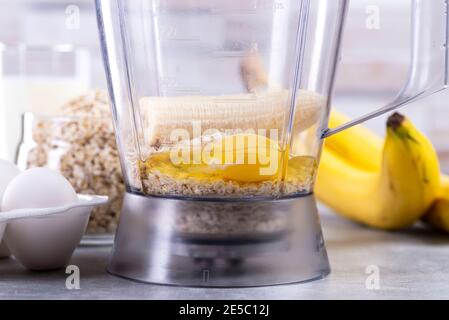 Avena e uova in un frullatore. Frittelle OAT con banana. Processo di cottura passo dopo passo. Banane, latte, uova, avena, sale Foto Stock