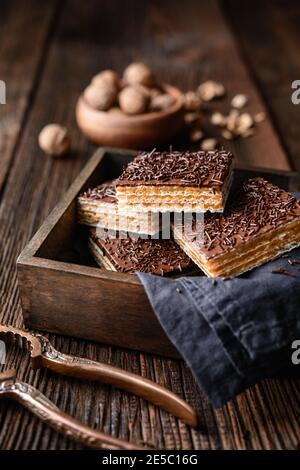 Cialda dolce fatta in casa, ripiena di noci e ricoperta con glassa di cioccolato su sfondo di legno Foto Stock