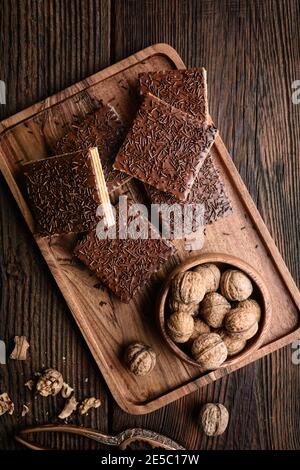 Cialda dolce fatta in casa, ripiena di noci e ricoperta con glassa di cioccolato su sfondo di legno Foto Stock