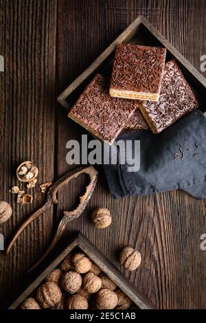 Cialda dolce fatta in casa, ripiena di noci e ricoperta con glassa di cioccolato su sfondo di legno Foto Stock