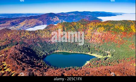 Lago di Sant'Ana, Transilvania, Romania, Europa. Splendido scenario autunnale con foresta colorata e idilliaco lago vulcanico, un popolare viaggio turistico Foto Stock