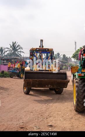 Nandakeshwar, Karnataka, India - 7 novembre 2013: Primo piano del bulldozer su strada sterrata sport leis fiori multipli per Diwali sotto il cielo d'argento w Foto Stock