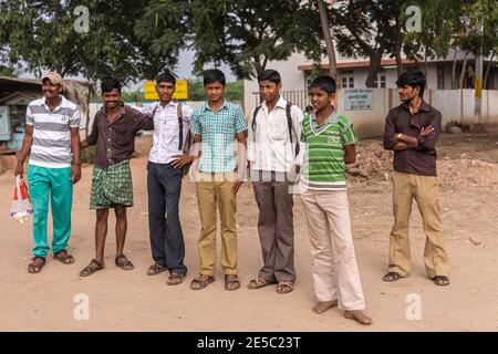 Nandakeshwar, Karnataka, India - 7 novembre 2013: Closeup di un gruppo di adolescenti di sesso maschile allineati su strada sterrata in attesa di autobus pubblico per andare a scuola. Foto Stock