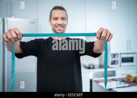 felice uomo nutrizionista attraente di idoneità con il nastro di misurazione al moderno cucina Foto Stock