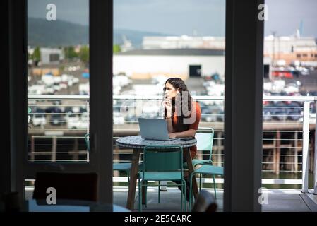 Donna con computer portatile che lavora al tavolo sul patio Foto Stock