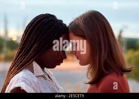 Due giovani donne si abbracciano seriamente. Concetto multietnico Foto Stock