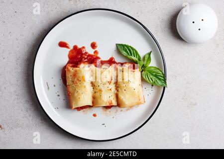 Pasta ripiena con frutti di mare e formaggio in salsa di pomodoro. Foto Stock