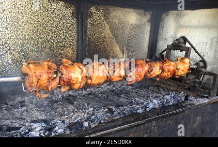 Polli interi fritti croccanti su uno spiedino in un pranzo bar cucina - rotisserie Foto Stock