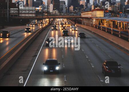 Skyline della città e auto che guidano lungo la superstrada al tramonto, Chicago, Illinois, USA Foto Stock