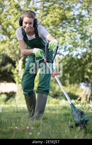 il giardiniere femminile falcia l'erba nel giardino Foto Stock