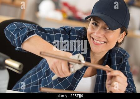 donna felice taglia tubi di rame Foto Stock