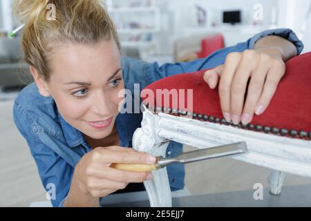 attraente designer di mobili femminile soddisfatto levigare con cura una sedia Foto Stock