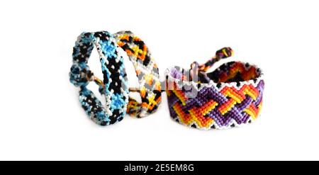 Fuoco selettivo di bracciali di amicizia intrecciati con colori brillanti motivi fatti a mano di filo su sfondo bianco Foto Stock