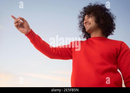UN GIOVANE CON CAPELLI RICCI IN PIEDI E FELICEMENTE PUNTATO VIA Foto Stock