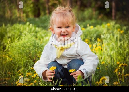 bambina sul prato dei dandelions in primavera Foto Stock