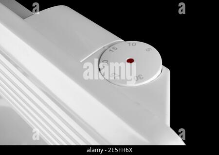 Batteria del riscaldatore elettrico isolata su sfondo nero. Radiatore. Convettore riscaldatore elettrico domestico isolato. Convettore di riscaldamento. Closeup del termostato Foto Stock