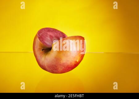Mela con polpa rossa all'interno con un cuneo tagliato. Sfondo giallo isolato. Frutta esotica, cibo sano Foto Stock