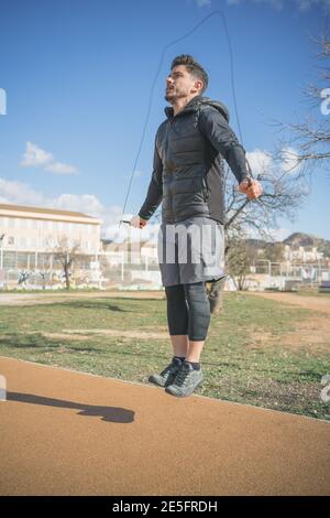 uomo atletico che fa la corda saltando l'esercizio nel parco all'aperto Foto Stock