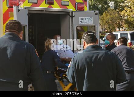 Los Angeles, Stati Uniti. 28 Gennaio 2021. I medici vigili del fuoco di Los Angeles guidano un paziente su un gurney ad un'ambulanza di attesa per trasferirlo dal Martin Luther King Hospital ad un'altra struttura mercoledì 27 gennaio 2021. La popolazione servita da MLK è in gran parte latino e nero, entrambe le comunità che sono state duramente colpite dalla pandemia. Molti residenti vivono in alloggi densi e multigenerazionali, lavorano lavori essenziali e soffrono di condizioni sanitarie secondarie a causa di una mancanza sistemica e permanente di accesso a cure primarie di qualità. Foto di Jim Ruymen/UPI Credit: UPI/Alamy Live News Foto Stock