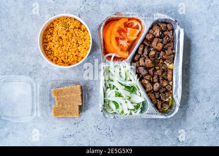 Take away turco Kebab fegato con cipolle e pomodori dentro Piatto di Tabldot servito con semola Irmik Dessert e Bulgur O Bulghur riso Pilaf Pilav Foto Stock