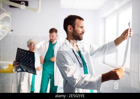 I medici che esaminano un rapporto sui raggi X in ospedale per effettuare la diagnosi Foto Stock