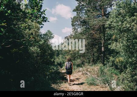 Ragazza che cammina lungo un piccolo sentiero nella montagna di Prades, Tarragona, Spagna. In una soleggiata giornata estiva Foto Stock