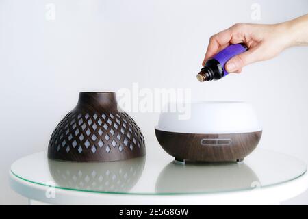 Donna mano che gocciola gli oli essenziali di lavanda in un diffusore Foto Stock