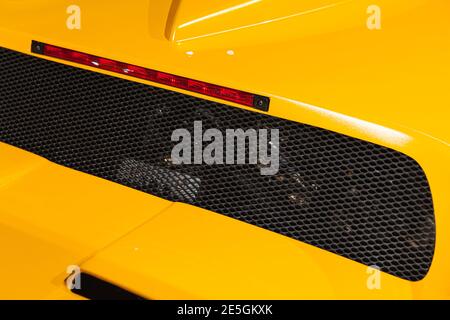 Frammento di roadster giallo di lusso. Griglia di ventilazione posteriore e luci di arresto. Design auto italiano Foto Stock