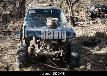 Abbandonata auto rotta SUV in piedi su un'erba secca durante il giorno, vista frontale Foto Stock