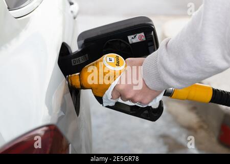 Uomo che maneggia con una carta un carburante di benzina di pompaggio giallo per rifornire una macchina grigia Foto Stock