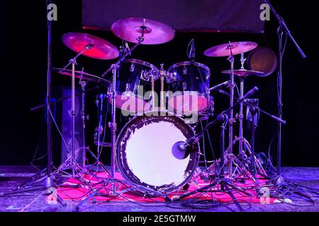 Il tamburo impostato sul palco. Il drum kit si trova in uno spazio buio ed è illuminato dalla luce al neon. Foto Stock