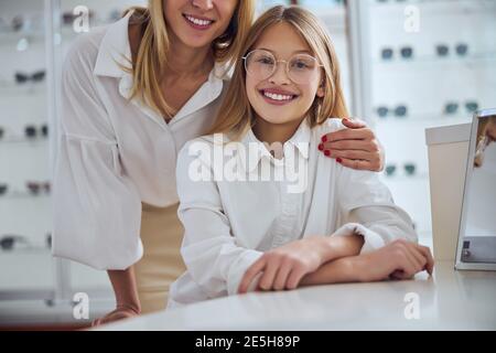 Elegante ragazza di scuola affascinante con la madre che passa il tempo in oftalmologia centro Foto Stock