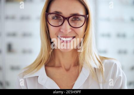 Felice sorridente bionda caucasica donna provante insieme di occhiali Foto Stock