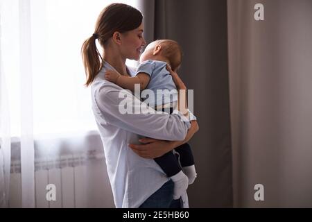 Positivo felice giovane genitore lulling suo bambino Foto Stock