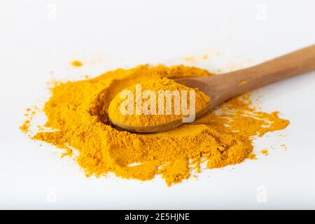 Polvere di curcuma o curcuma. Polvere curcuma in un cucchiaio di legno posare piatto isolato su sfondo bianco. Foto Stock