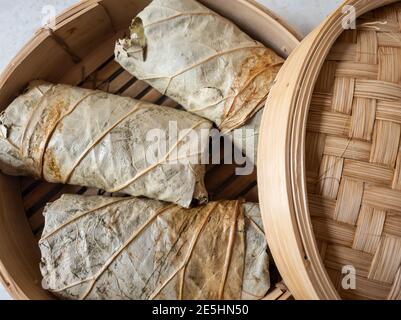 Riso appiccicoso avvolto in foglie di loto pronto per la cottura a vapore. Foto Stock