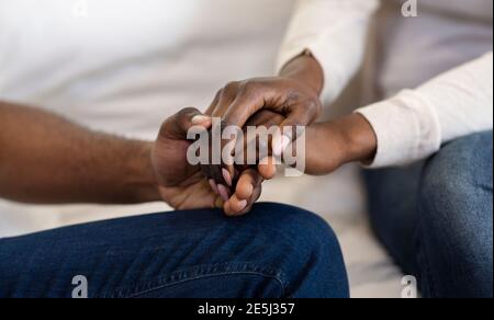 Vista dettagliata del nero donna e uomo Holding Hands, seduti sul divano insieme, panorama Foto Stock