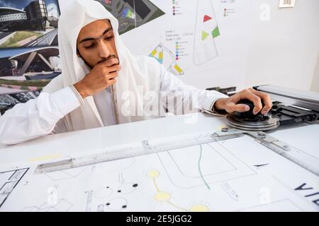 Architetto arabo che prepara la sua scrivania e pensa a nuove idee Foto Stock