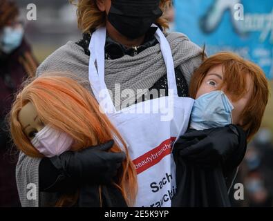 Dresda, Germania. 28 Gennaio 2021. Un partecipante tiene due bambole per parrucchieri in mano durante un'azione di protesta della gilda dei parrucchieri di Dresda e dei Cosmeticians sui prati dell'Elba. Con l'azione, l'Arte dei parrucchieri di Dresda richiama l'attenzione sulla situazione devastante della pandemia di Crona delle società di parrucchieri e cosmetici. Credit: Robert Michael/dpa-Zentralbild/dpa/Alamy Live News Foto Stock