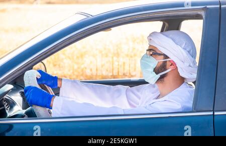 Uomo arabo che guida un'automobile nella pandamic Foto Stock