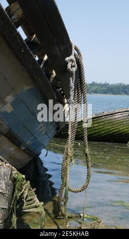 Corda drappeggiato sul lato di una vecchia barca marcio. Foto Stock