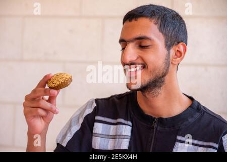 L'uomo musulmano sta mangiando falafel e godendo il suo tempo Foto Stock