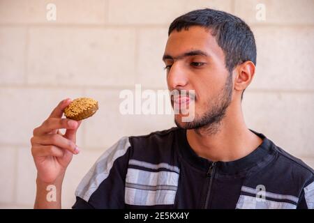 L'uomo musulmano sta mangiando falafel e godendo il suo tempo Foto Stock