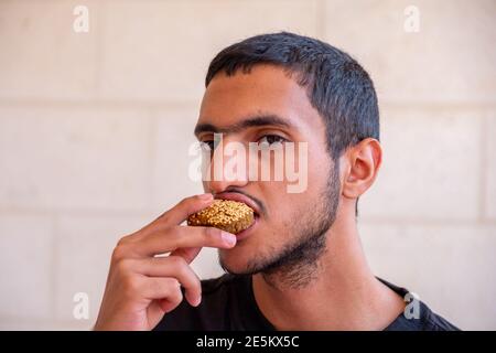 L'uomo musulmano sta mangiando falafel e godendo il suo tempo Foto Stock