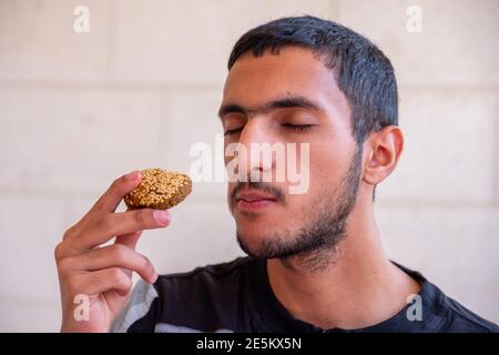 L'uomo musulmano sta mangiando falafel e godendo il suo tempo Foto Stock